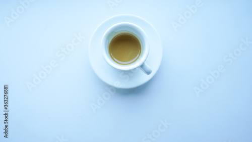 white cup and plate fill with coffee espresso on white table beside window light cool tone top view center stock photo