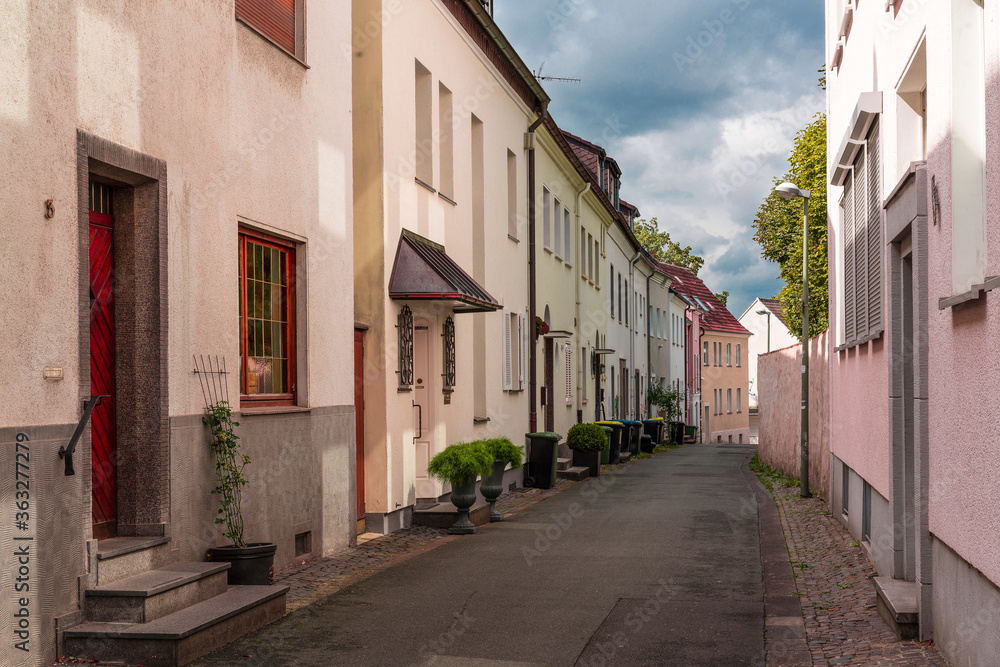 Narrow city street with houses in warm pink tones and the cold gray sky.