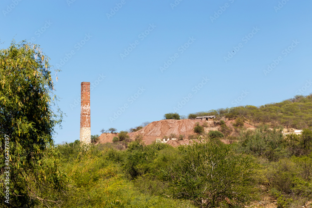 Disused brick smokestack Julia, and rest of industrial mining ruin in hill of former mine in the town of El Triunfo, Baja California Sur, Mexico Disused brick smokestack Julia, and rest of industrial mining ruin in hill of former mine in the town of El Triunfo, Baja California Sur, Mexico