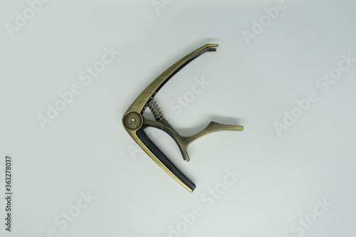 Golden guitar capo selected on white background, close up.