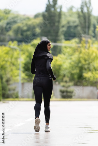 young arabian sportswoman in hijab and sportswear jogging outside