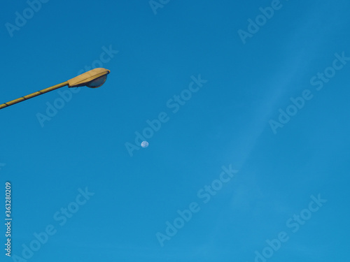 The street light tower on the background is blue sky And there is a small moon in the middle © Thawatchai Images