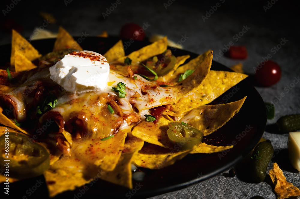 Foto Stock Mexican ham cheese nachos topped with pork, sour cream
