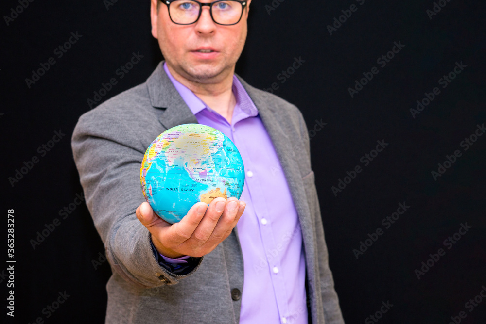 Close up of businessman holding digital globe in palm global business communications concept.Black wall. Close up of businessman holding digital globe in palm global business communications concept.Black wall.