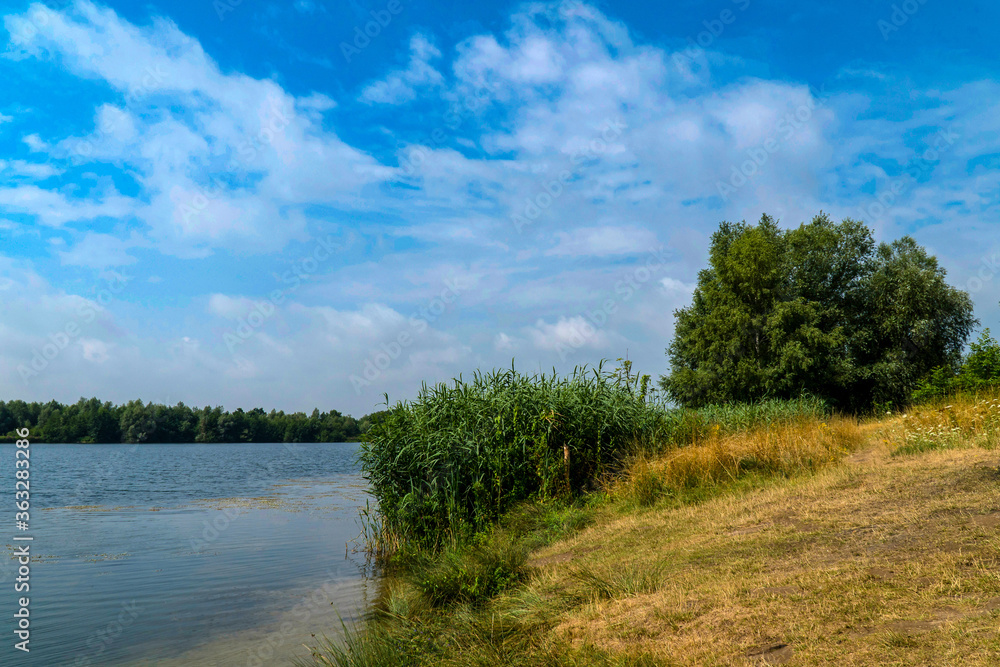 Picturesque lake on a sunny day. Light, white clouds in the blue sky. Picturesque lake on a sunny day. Light, white clouds in the blue sky.