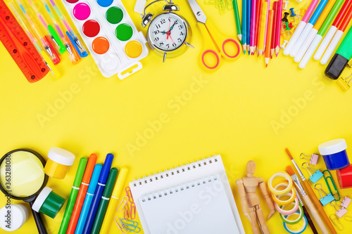 Various school office and painting supplies on yellow background. Back to school concept. Top view. Copy space