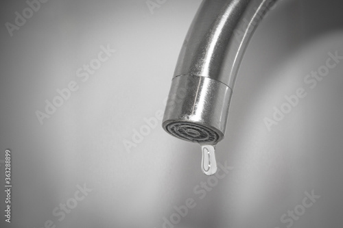 A drop of water hangs from the tap. Fluid leaks and drop down.The concept of lack of drinking water.