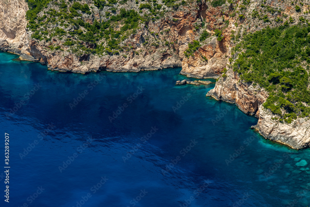 Rocky coast covered with green bushes and the deep blue sea in the west of Zakynthos, Greece