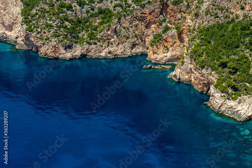Rocky coast covered with green bushes and the deep blue sea in the west of Zakynthos, Greece