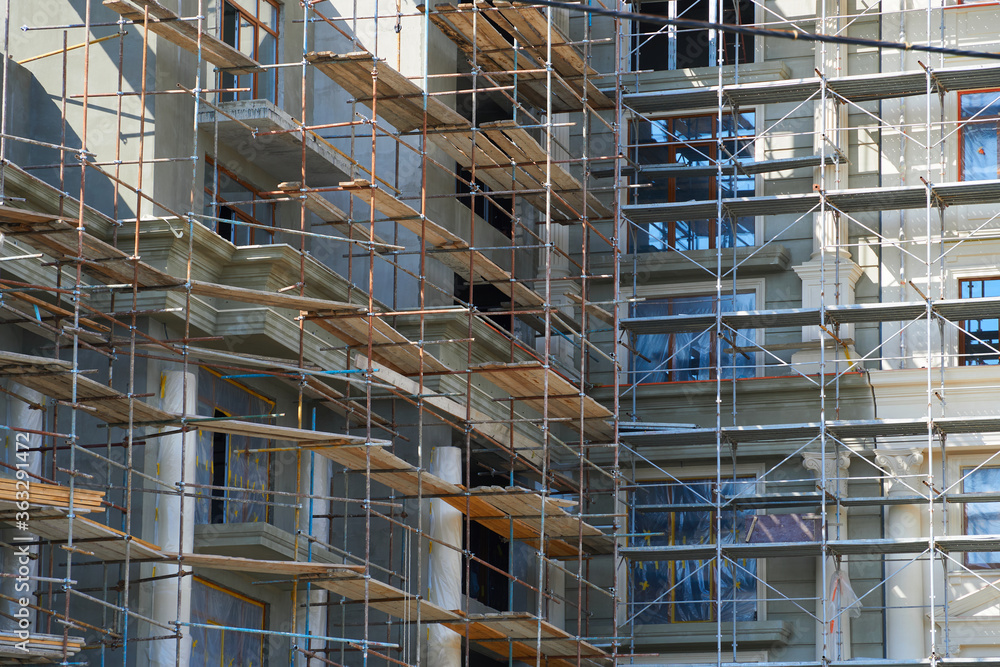 modern building under construction, plastered walls and scaffolding, construction crane