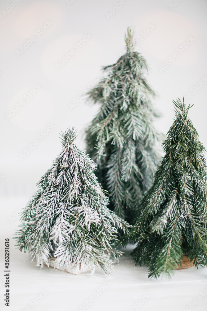 Christmas little trees and golden lights bokeh on white background. Winter  magic forest, festive modern decor. Miniature handmade pine trees with  snowy branches. foto de Stock | Adobe Stock