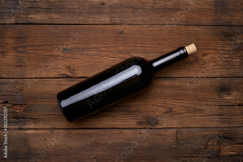 Red wine bottle on wooden table background. Top view with copy space. Mockup.