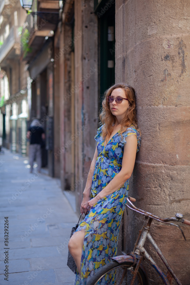 Fototapeta premium Beautiful girl with a bicycle on the street of an ancient city.