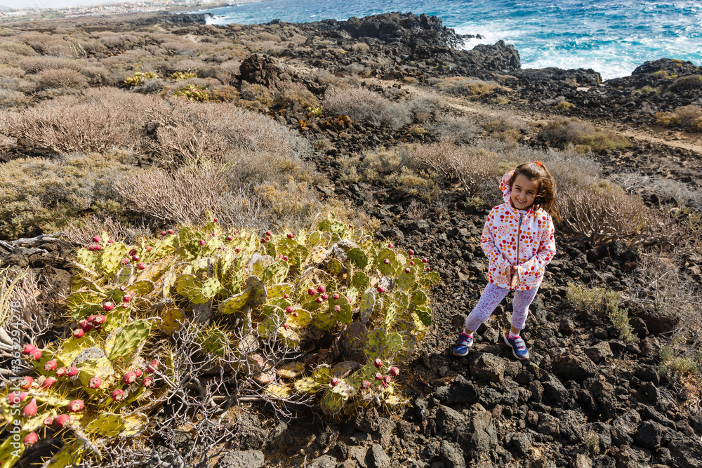 Fototapeta premium little girl stands near a cactus on the island of tenerife