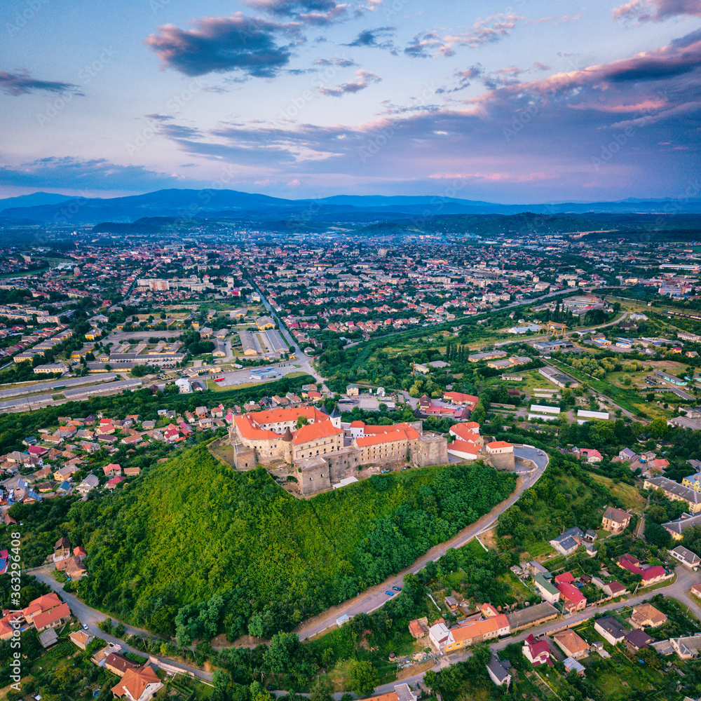 Aerial view of medieval castle Palanok, Mukachevo (Munkacs), Transcarpathia (Zakarpattia), Ukraine. Summer landscape with old architecture, green trees and town, outdoor travel background