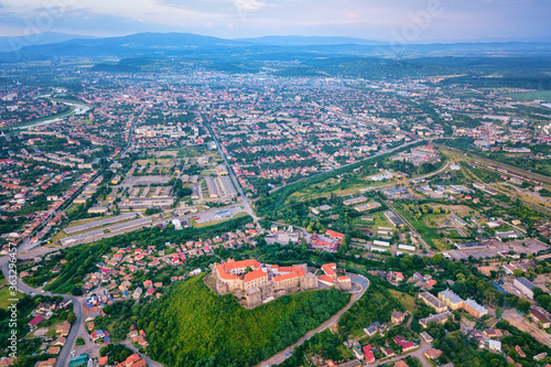 Aerial view of medieval castle Palanok, Mukachevo (Munkacs), Transcarpathia (Zakarpattia), Ukraine. Summer landscape with old architecture, green trees and town, outdoor travel background