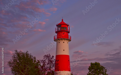 A small and beautiful lighthouse in the evening dawn sunset with pink clouds and bright light in Falshöft, Germany