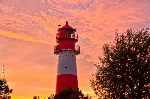 A small and beautiful lighthouse in the evening dawn sunset with pink clouds and bright light in Falshöft, Germany