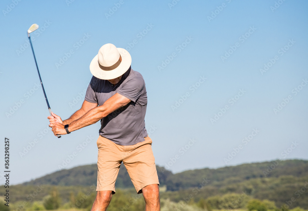 Golfing man swinging on a golf course golf concept Golfing man swinging on a golf course golf concept