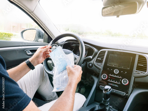 Man opening an envelope with face masks in the car © karrastock