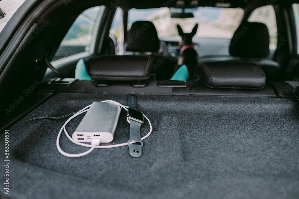 powerbank battery charge smartwatch on travel. Close up photo of powerbank in the car charging fitness smart watch tracker. powerbank battery charge smartwatch on travel. Close up photo of powerbank in the car charging fitness smart watch tracker.