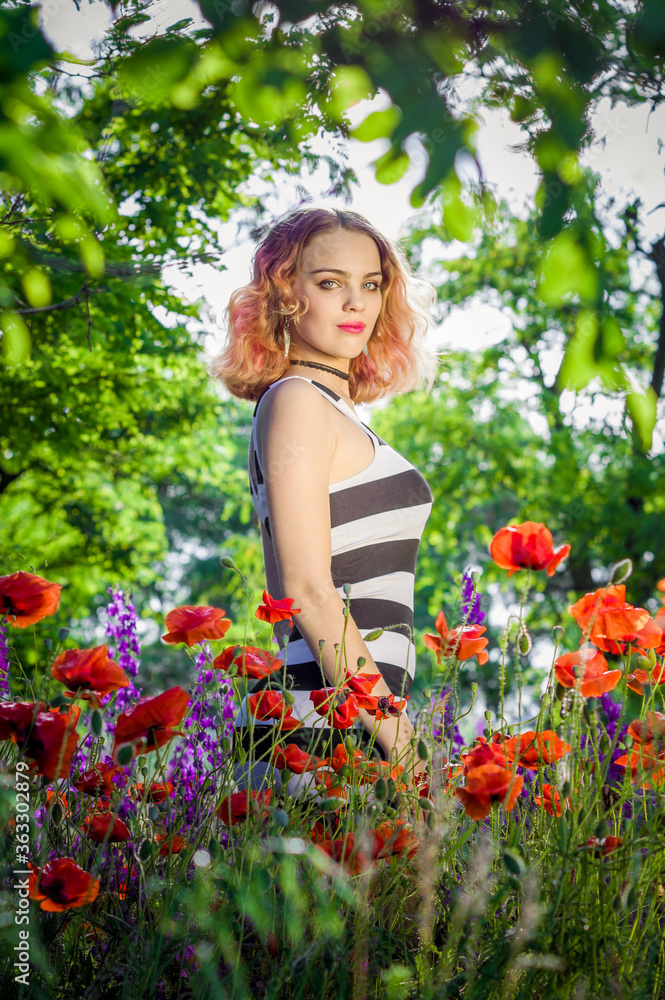 A lovely young girl in a striped dress stands on a poppy field A lovely young girl in a striped dress stands on a poppy field