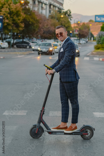 Young bussinesman with electric scooter posing during work break.