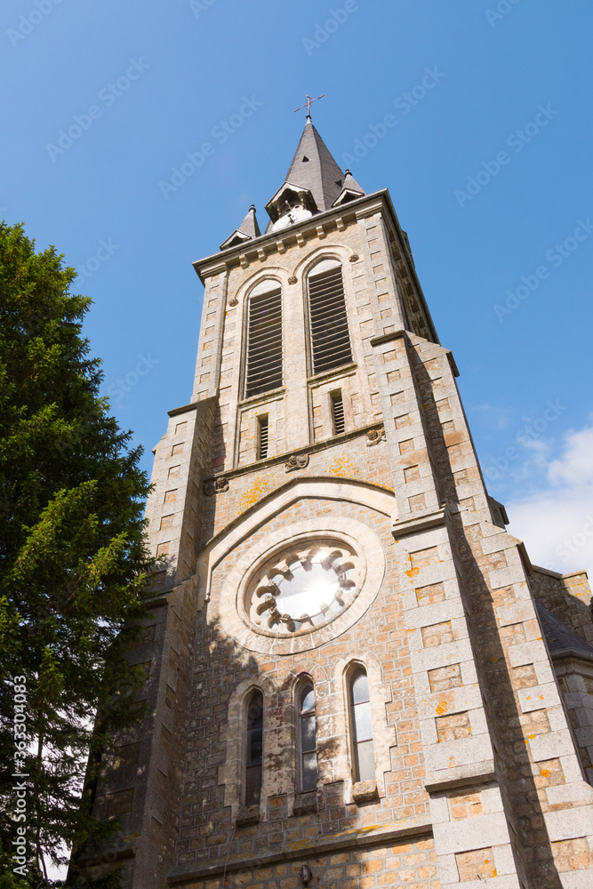 Beautiful close up of Notre-Dame-de-l'Assomption church tower (La Lande Patry, Normandy, France). Sunny day in the north of France. Stone christian church. Vertical shot.