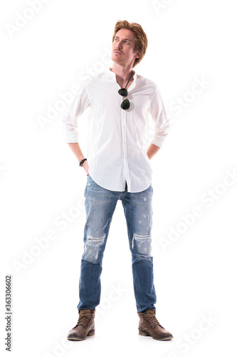 Thinking young stylish man looking up planning mindful with hands behind back. Full body length isolated on white background. 