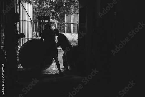 Workers, loader. Hard work. Acceptance of goods at the warehouse. industry, paper mill. The concept of low-paid, harmful work. Place for text. Black and white. copy space