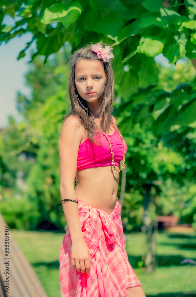 Model looking Girl in a pink topic posing on the background of green grass and forest. Model looking Girl in a pink topic posing on the background of green grass and forest.