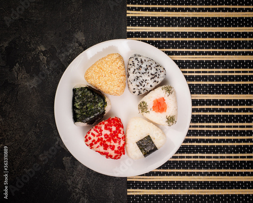 different handmade onigiri close-up. Japanese cuisine, Asian vegan menu. many ingredients - nori, pepper, rice, sesame, chia.