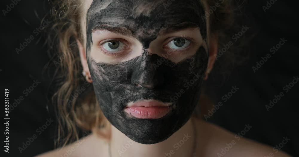 Girl with coal mask on skin looking at the camera Girl with coal mask on skin looking at the camera