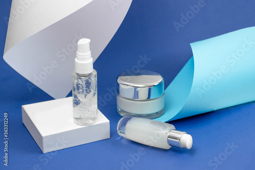 Cosmetic bottles with serum, gel, face cream on a blue background. Skin cosmetics, minimalism. The concept of salon procedures.