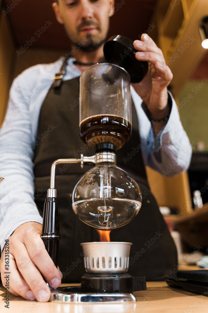 Syphon coffee brewing process. Close up syphon is heating by fire. Brewing photo on the fire. Alternative method of coffee making. Vertical photo for advert in social networks