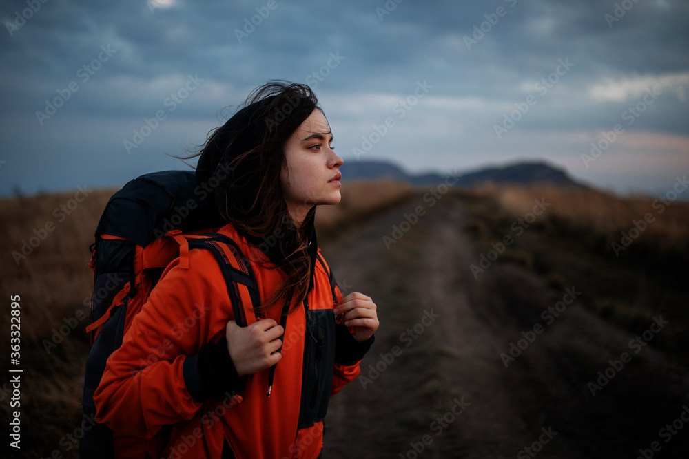 Portrait of a tourist girl with a backpack. Young beautiful woman traveling in the mountains