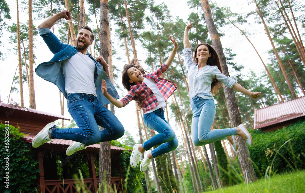 Young happy and excited family are having fun and jumping together on suburban house backgrounds.