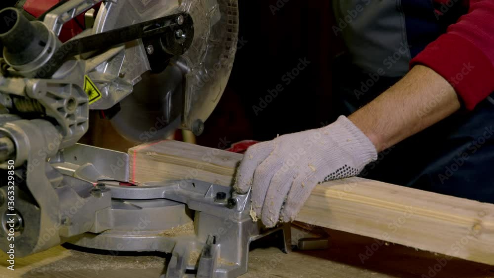 Male carpenter uses Circular Saw with laser Cutting New Baseboard for