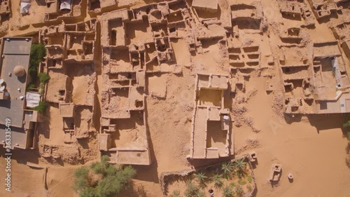 Top down aerial drone shot flying over the desert town of Chinguetti, Mauritania. Slowly gliding over the buildings showing the shapes of the structures  against the desert sand.