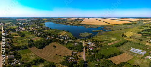 street and Blue pond on the Zelenchuk II river near the village of Peschanoe  Krasnodar Territory  South of Russia  surrounded by wheat fields - aerial drone small panorama on a sunny day