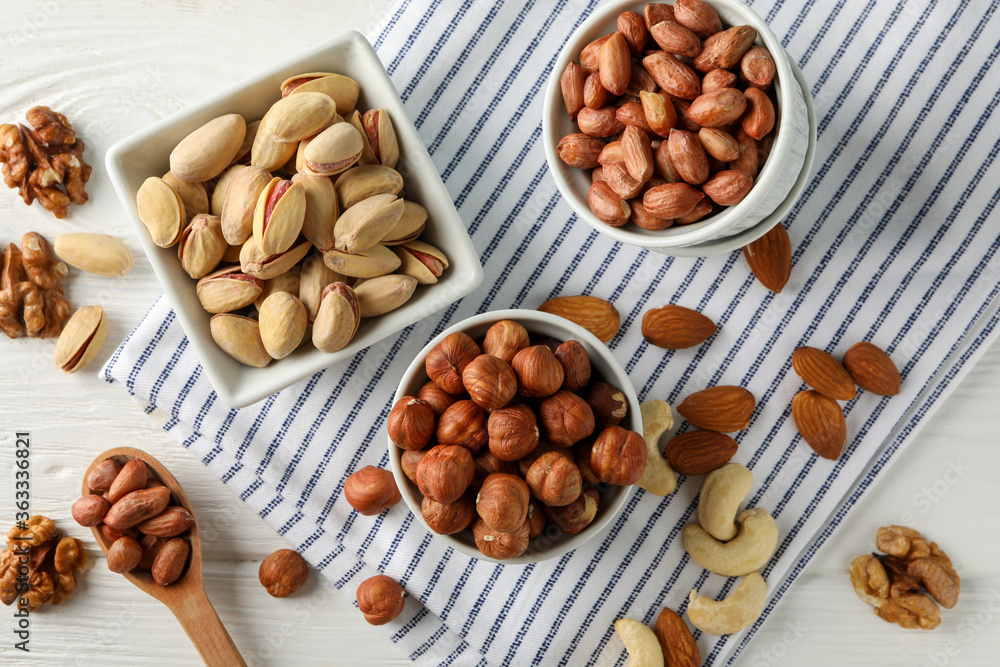 Bowls with different nuts on white wooden background. Vitamin food Bowls with different nuts on white wooden background. Vitamin food