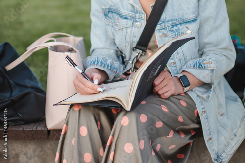 Girl draws in sketchbook in the park. Front view