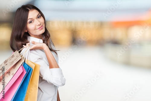 Young woman with shopping bags on blurred shopping mall background