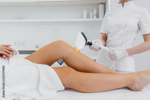 A beautiful young girl will perform a laser hair removal procedure with modern equipment in the Spa salon close-up. Beauty salon. Body care