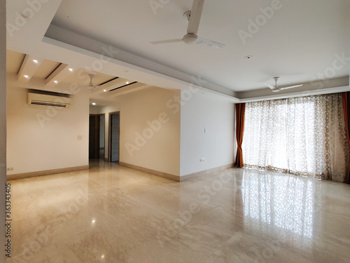 Wide angle shot of a huge apartment with false ceiling lights  curtains on windows polished marble floor