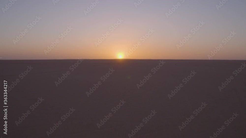 Aerial drone shot traveling through the desert towards the sunset on the horizon. Aerial drone shot traveling through the desert towards the sunset on the horizon.