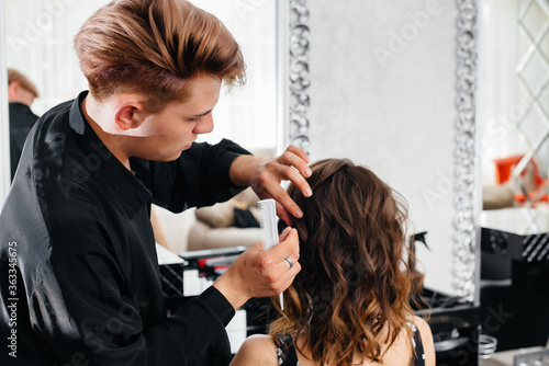 In a beautiful, modern beauty salon, a professional stylist makes a haircut and hairstyle for a young girl. Beauty, and fashion