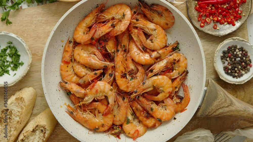 Roasted Prawns on frying pan served on white wooden cutting board Roasted Prawns on frying pan served on white wooden cutting board