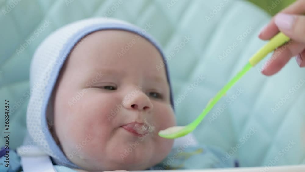Mother feeds small child healthy food from spoon. Family care and maintenance. Feeding baby cream soup. Healthy child nutrition. Mother feeds small child healthy food from spoon. Family care and maintenance. Feeding baby cream soup. Healthy child nutrition.