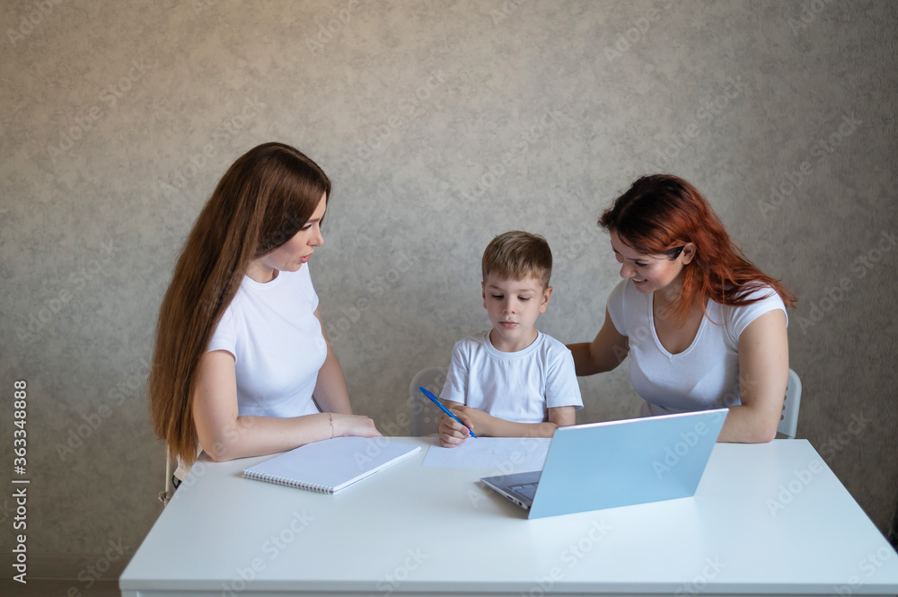 Two women help the boy do school homework. Female tutor teaches a child at home in the kitchen. The school teacher conducts an individual lesson. Mother helps her son to study. Two women help the boy do school homework. Female tutor teaches a child at home in the kitchen. The school teacher conducts an individual lesson. Mother helps her son to study.